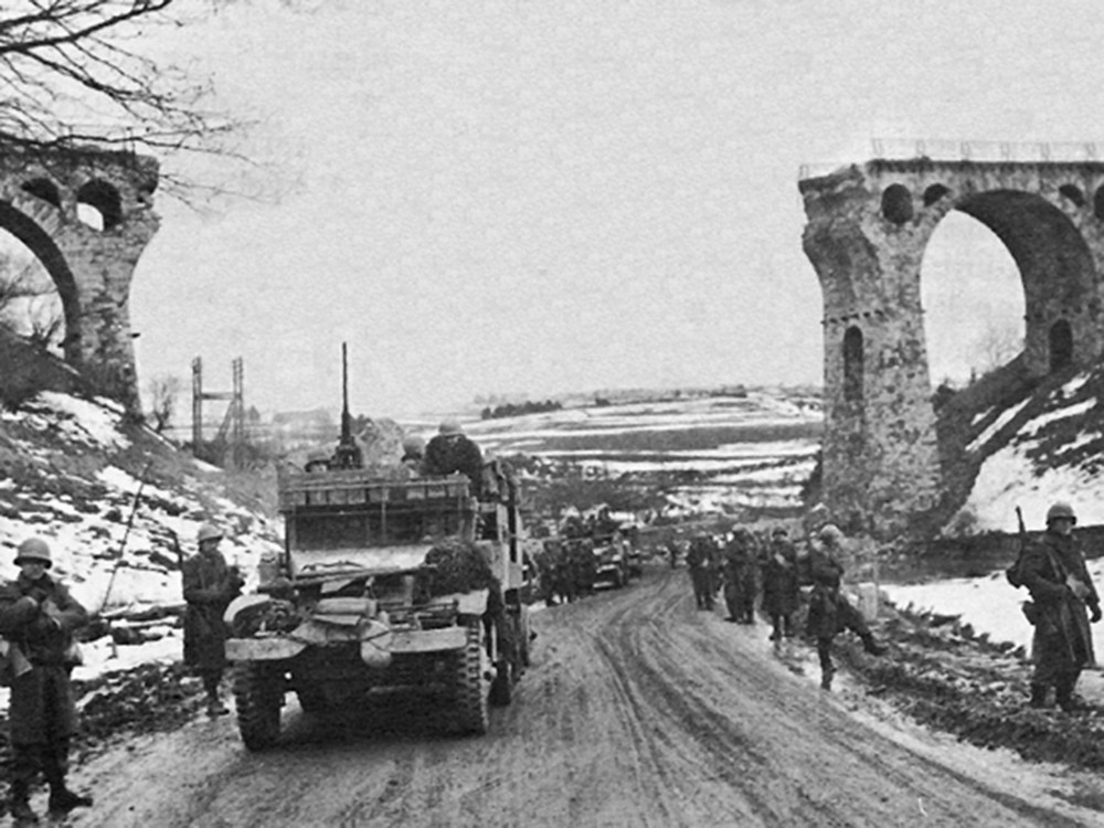 <p style="text-align: center;"><strong>The 1st Battalion of the US 26th Infantry Regiment passing through the railway viaduct north of B&uuml;tgenbach, Belgium - Late 1944.</strong><br style="text-align: center;" /><span style="text-align: center;">Source / Cr&eacute;dit :&nbsp;</span><a style="text-align: center;" href="https://commons.wikimedia.org/wiki/File:26th_Infantry_Regiment_near_Butgenbach.jpg" target="_blank" rel="noopener">US Army Center for Military History - Wikipedia CC</a></p>