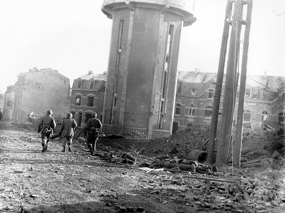 <p style="text-align: center;"><strong>Members of the 101st Airborne Division walk past dead comrades, killed during the Christmas Eve bombing of Bastogne, Belgium, the town in which this division was besieged for ten days. This photo was taken on Christmas Day. 1944.</strong><br style="text-align: center;" /><span style="text-align: center;">Source / Cr&eacute;dit :&nbsp;</span><a style="text-align: center;" href="https://history.army.mil/html/reference/bulge/botb_images_01.html" target="_blank" rel="noopener">U.S. Army Center of Military History</a></p>